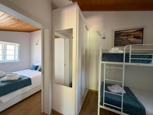 Quarto luminoso na Casa Azul com cama de solteiro, beliche e casa de banho privada, vista para o jardim