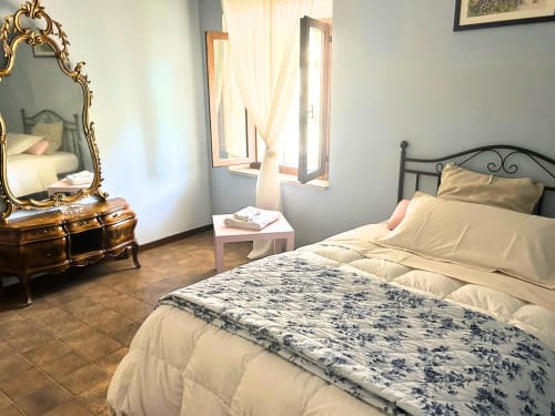 Camera da letto luminosa nell'appartamento L'Aia at colonna di Montarrenti, Siena con specchio ornamentale e letto in ferro battuto