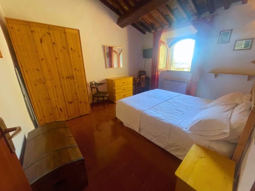 Camera spaziosa al B&B Torre Della Chiocciola di Monteriggioni con armadio in legno, letto e vista sulla terrazza