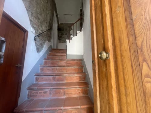 Scala con pavimenti in cotto e ringhiera in legno che sale verso il piano superiore dell'appartamento nel borgo di torniella, roccastrada, grosseto