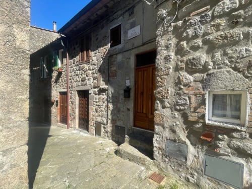 Affascinante vicolo in pietra con rustiche porte in legno, ingresso in appartamento nel borgo di torniella,
