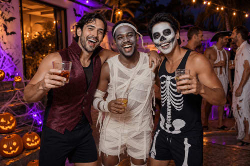 Trois hommes en costumes d'Halloween à la soirée de l'hôtel Cinq & Sept à Roujan avec des verres et un éclairage violet