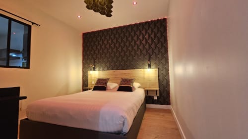 Chambre moderne à la Résidence L'Hermitière avec lit queen-size, tête de lit piquée, éclairage ambiant et parquet
