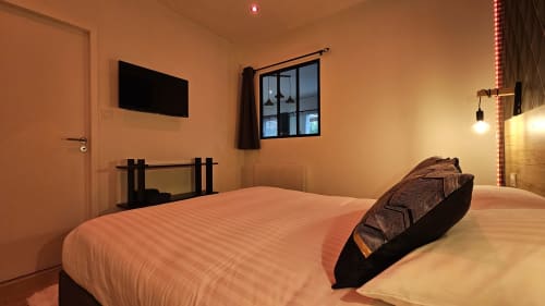 Chambre moderne à la Résidence L'Hermitière avec lit queen-size, TV écran plat, vue sur le lac et éclairage ambiant chaleureux