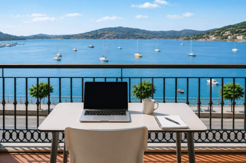 Espacio de trabajo frente al mar en el Hotel Holibai de Baiona con vista a veleros y bahía mediterránea