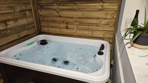 Jacuzzi spa avec jets d'eau bouillonnants dans un cadre extérieur clôturé en bois à la Résidence L'Hermitière.