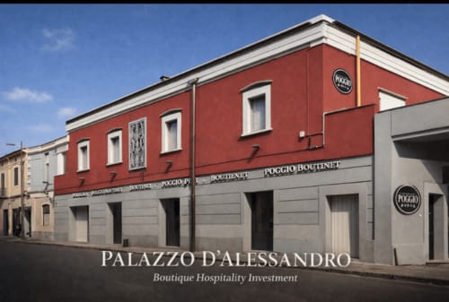 Facciata esterna dell'hotel boutique Palazzo D'Alessandro ad Anacapri con facciata superiore rossa e livello terra grigio affacciato su Poggio