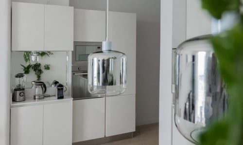 Cuisine blanche moderne avec suspension en acier inoxydable et appareils électroménagers à l'appartement Riviera Home de Roquebrune-Cap-Martin