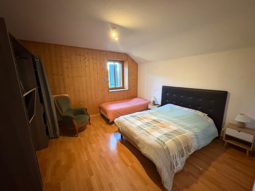 Chambre spacieuse à l'Auberge Du Ruxelier avec lit queen, lit simple, murs en bois et vue sur le jardin à Chenimenil