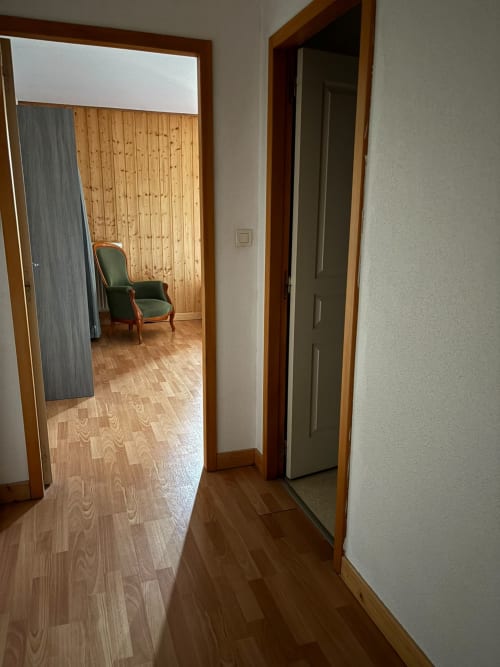 Couloir de l'Auberge Du Ruxelier avec parquet, porte de chambre et fauteuil vert reflété dans le miroir