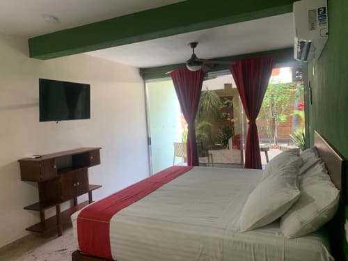 Habitación moderna en hotel La Morada, Monte Gordo con cama, TV y acceso a patio con vistas al jardín