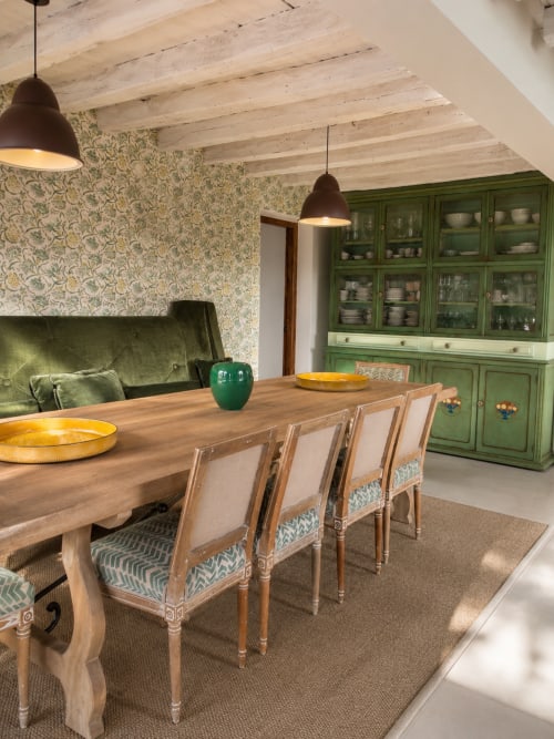 Rustic dining room at El Escondite De Pedro Malillo with wooden table, green cabinets, and beamed ceiling in Candeleda