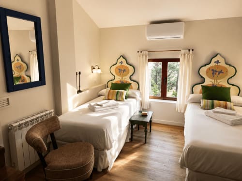 Bright twin bedroom at El Escondite De Pedro Malillo in Candeleda with decorated headboards, white linens, and wooden floors