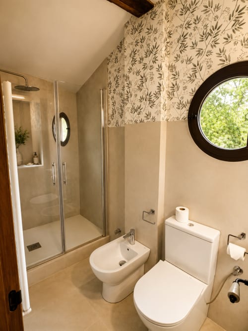 Modern bathroom at El Escondite De Pedro Malillo in Candeleda with shower, toilet, bidet, and circular window