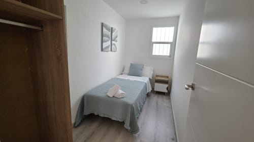 Dormitorio compacto en Siesta 7 Bajo Apartamento en Benicàssim con cama individual, armario de madera, ventana y comodidades modernas