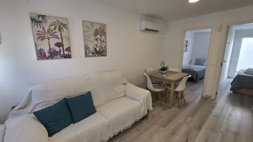 Luminoso salón de planta abierta con sofá color crema, mesa de comedor y vistas al jardín en apartamento costero de Benicàssim