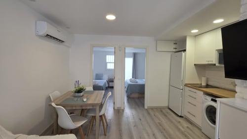 Cocina moderna y comedor en la casa rural de Benicàssim con dormitorios visibles a través de puertas de vidrio