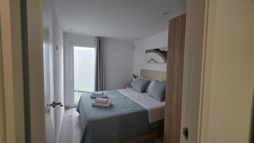Dormitorio moderno en casa rural de Benicàssim con vista al jardín, cama queen, detalles azules y puerta de patio