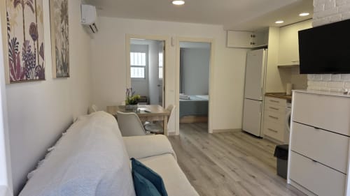 Interior moderno de apartamento en Benicàssim con cocina, sofá cama, comedor y vista al jardín