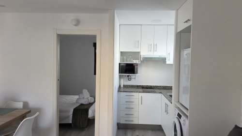 Cocina moderna de apartamento con gabinetes blancos, encimeras de granito y electrodomésticos en la casa de campo de Benicàssim