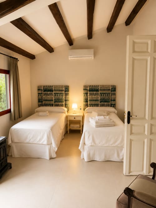 Twin bedroom with white bedding and decorative headboards at El Escondite De Pedro Malillo, Candeleda