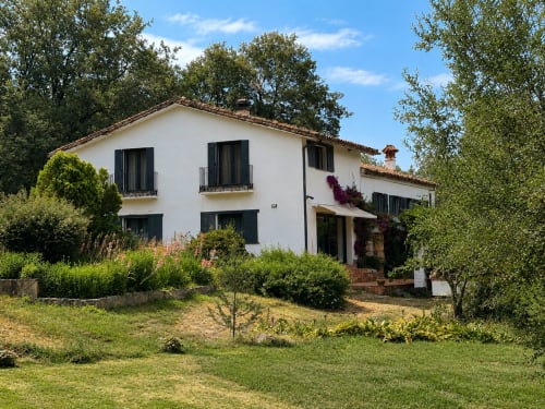 White rural villa with black windows surrounded by lush gardens in Candeleda, Spain - El Escondite De Pedro Malillo