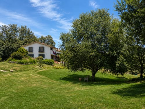White villa surrounded by lush green gardens and trees at El Escondite De Pedro Malillo, a bed and breakfast in Candeleda,