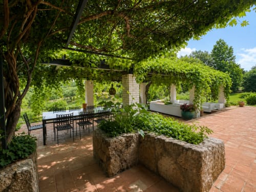 Lush pergola dining area at El Escondite De Pedro Malillo in Candeleda with stone seating and ivy-covered structures