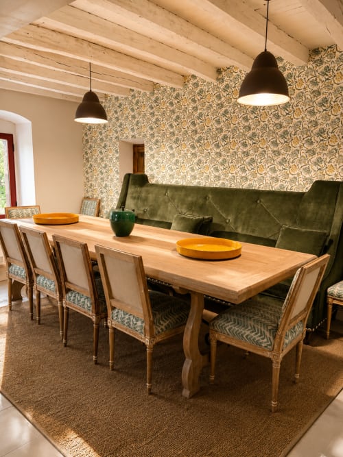 Elegant dining room at Casa Alardos villa in Candeleda with wooden table, patterned wallpaper, green velvet sofa, and pendant