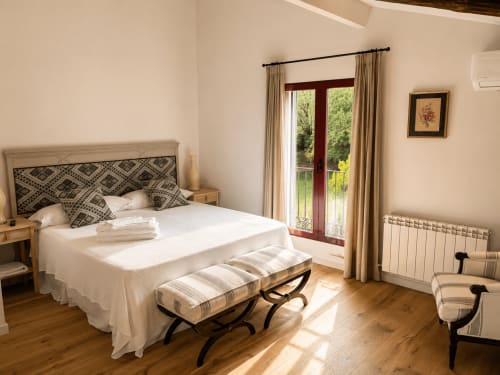 Bright bedroom in Casa Alardos villa, Candeleda, with queen bed, patterned headboard, and terrace doors