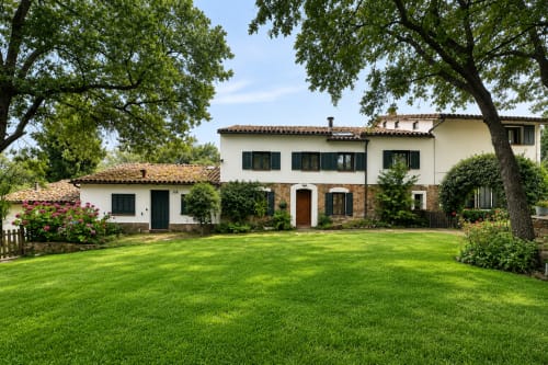 Casa Alardos villa in Candeleda with white stone facade, manicured lawn, and tree-shaded courtyard