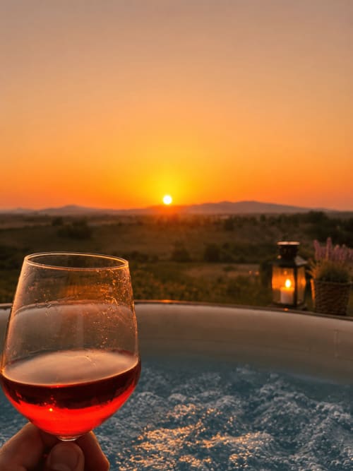 Bicchiere di vino rosso al tramonto con vista sulla campagna toscana a Il Poggio di Musignano, Canino