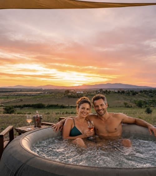 Coppia che si rilassa nella vasca idromassaggio al tramonto con vista sulla campagna toscana a Il Poggio di Musignano