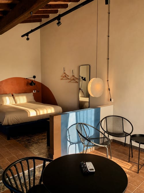 Studio moderno con testata in terracotta curva, lampada a sospensione e sedie nere al tavolo a Canino, Italia