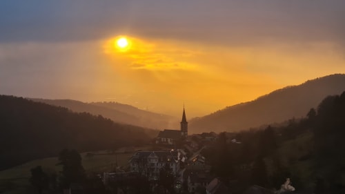 Lever de soleil sur le village de Thannenkirch niché dans les montagnes avec son clocher, vue montagnarde idéale depuis les Gîtes d'Avalon