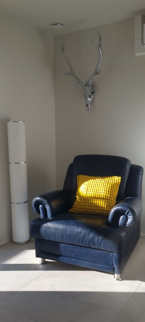 Fauteuil noir en cuir moderne avec coussin jaune dans l'appartement Les Gîtes d'Avalon, bois de cerf et décor blanc