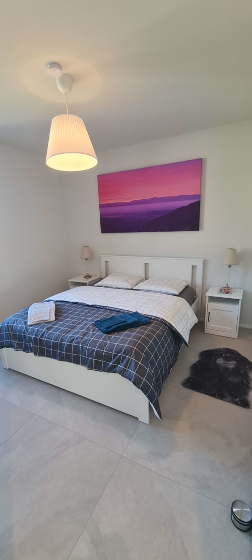 Chambre moderne aux Gîtes d'Avalon avec lit queen-size, lampe suspendue et tableau des montagnes colorées à Thannenkirch.