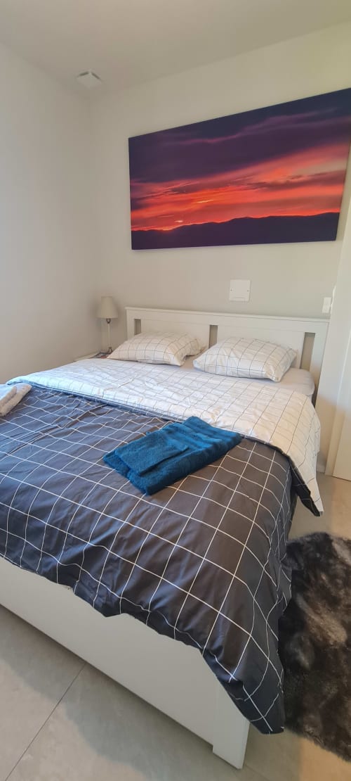 Chambre cosy aux Gîtes d'Avalon avec coucher de soleil montagneux, lit blanc et literie écossaise bleue