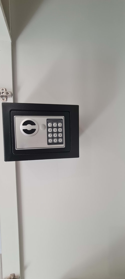 Coffre-fort électronique noir fixé au mur blanc de l'appartement Les Gîtes d'Avalon avec serrure à clavier numérique