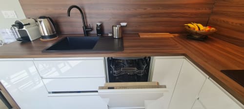Cuisine moderne des Gîtes d'Avalon avec plan de travail en bois, évier noir, bouilloire inox et lave-vaisselle