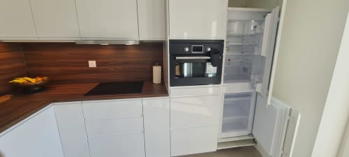Cuisine moderne aux armoires blanches, comptoir en bois foncé, four noir et réfrigérateur ouvert à Les Gîtes d'Avalon
