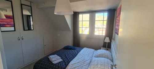Chambre moderne aux Gîtes d'Avalon avec vue montagne, literie bleue, armoire et lumière naturelle