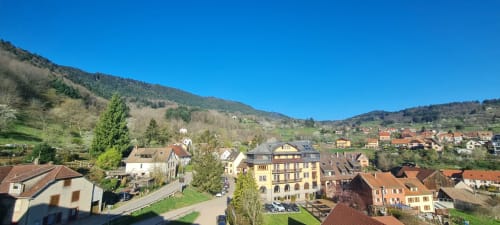 Vue pittoresque du village montagnard de Thannenkirch avec ses maisons traditionnelles nichées dans les collines de la vallée sous un ciel bleu dégagé