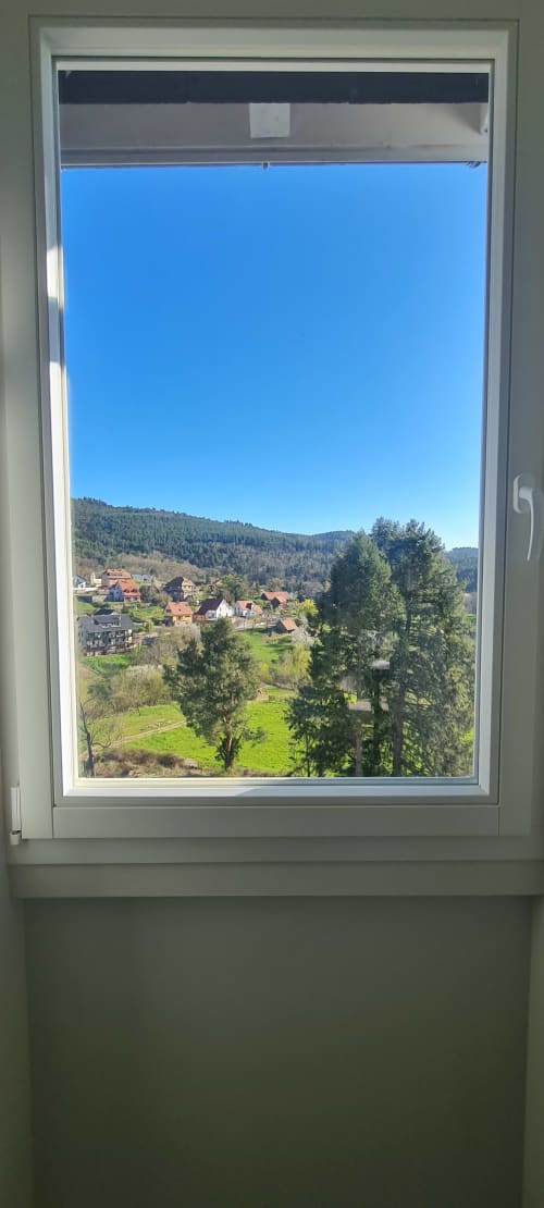Vue pittoresque de la vallée montagnarde depuis les Gîtes d'Avalon à Thannenkirch, avec collines boisées, prairies verdoyantes et architecture traditionnelle
