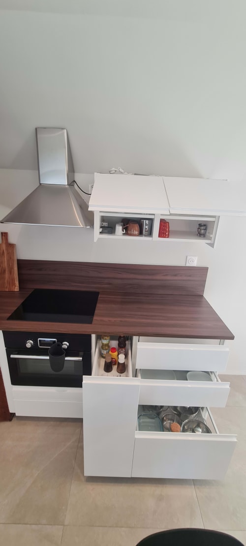 Cuisine moderne de l'appartement Les Gîtes d'Avalon avec plan de travail en bois foncé, armoires blanches, four noir et inox