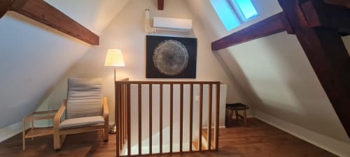Chambre mansardée cosy aux Gîtes d'Avalon avec lit bébé en bois, fauteuil, lampe et tableau circulaire à Thannenkirch, France