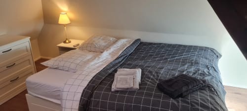 Chambre confortable aux Gîtes d'Avalon avec lits jumeaux, lampe de chevet, commode blanche et vue sur les montagnes à Thannenkirch