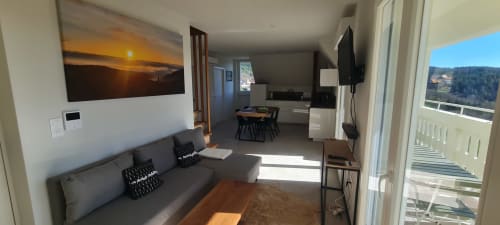 Séjour moderne aux Gîtes d'Avalon : canapé gris, coin repas, TV et balcon avec vue sur les montagnes à Thannenkirch