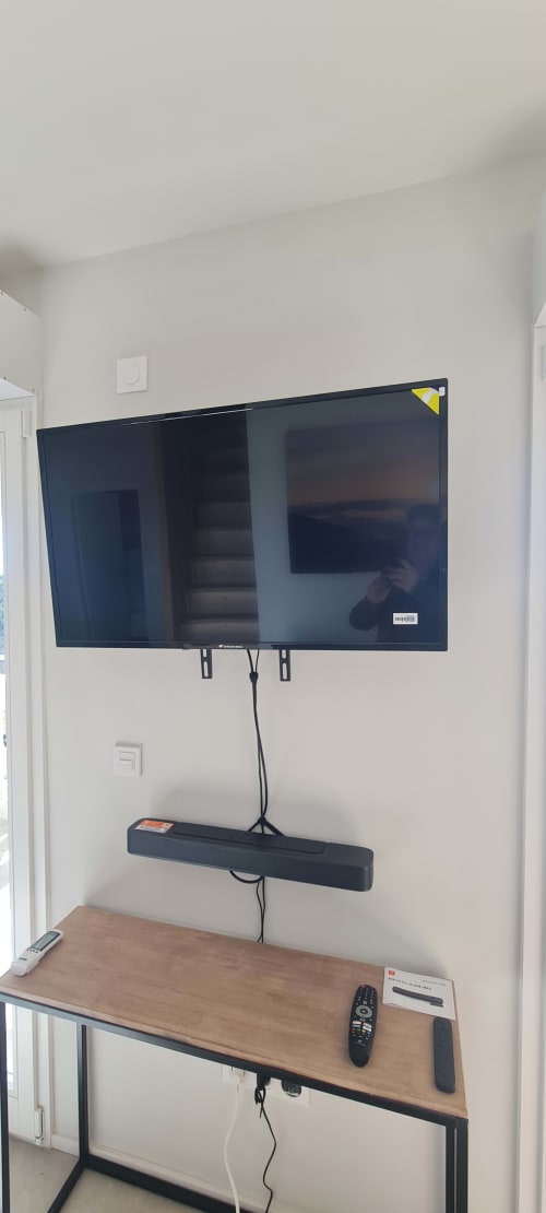 Téléviseur plat mural et barre de son au-dessus d'un bureau en bois dans l'appartement Les Gîtes d'Avalon, Thannenkirch