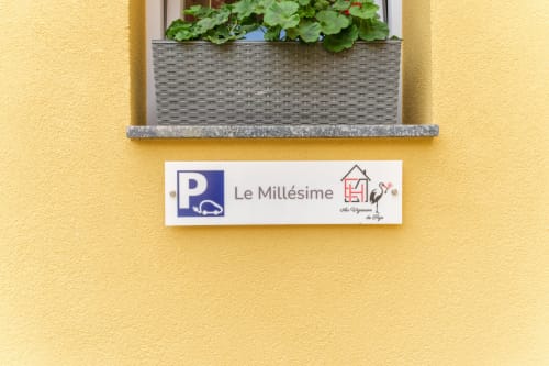 Le Millésime sign on yellow wall with window planter above, Sigolsheim hotel entrance
